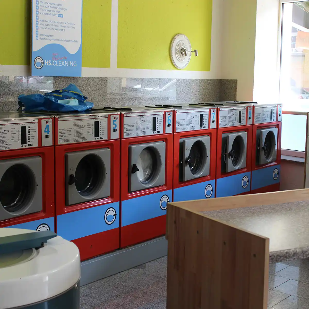 A row of washing machines with a red housing