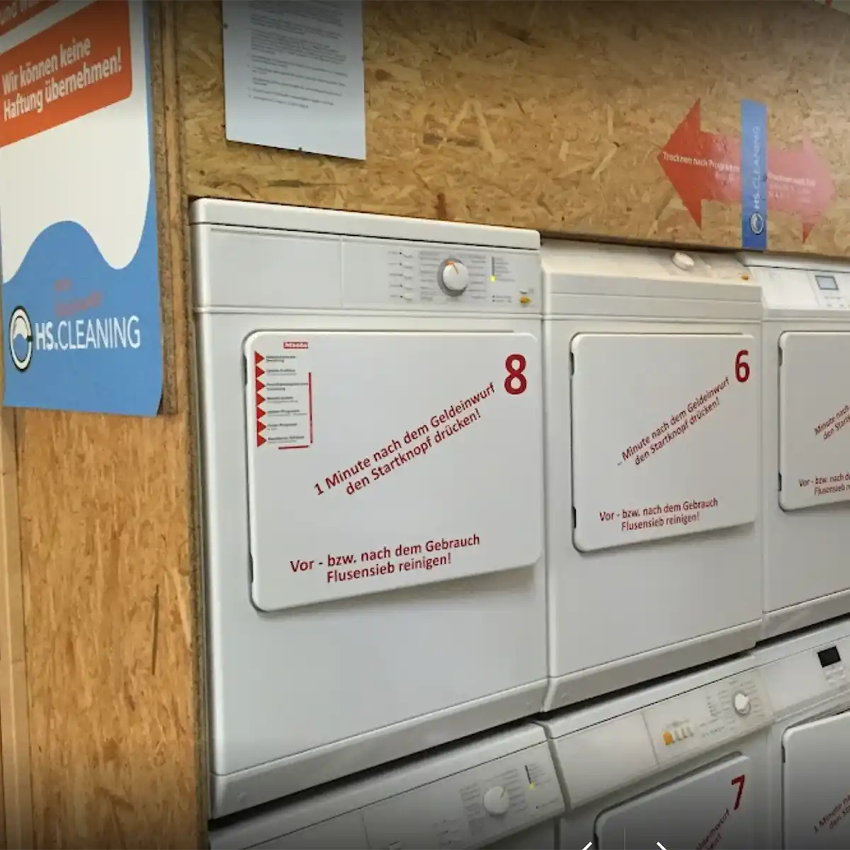 Two rows of white tumble dryers standing one on top of the other.